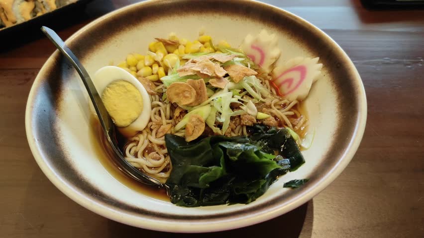 A bowl of garlic shoyu chicken ramen on wooden table