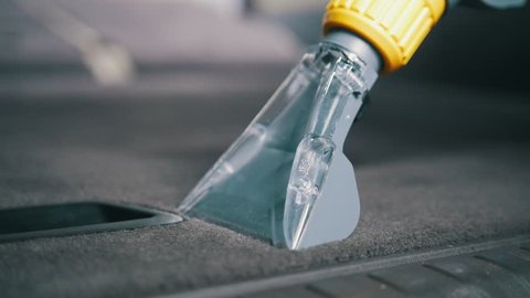 Car interior cleaning with vacuum cleaner, carpeted in the trunk