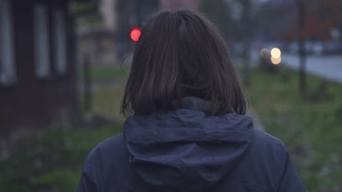 Rear view of disoriented female person walking down the street, handheld footage with selective focus Video Stok