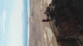 Photographer Man Traveler on Mountain Top Taking Pictures in Hverir Geothermal Area. Iceland. Aerial View. Drone is Orbiting. Vertical Video