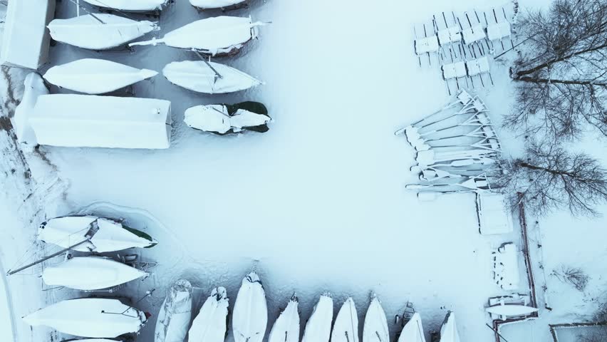 Yachts lined up in several rows and covered with a thick layer of snow. In winter, the yachts are taken out of the water.