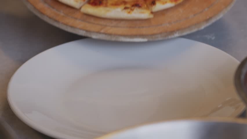 A man in an apron is putting raw pizza into a wood-fired pizza oven. Cooking food over an open fire. Natural food. Neapolitan pizza in the oven. Crumbling cheese on the surface of the pizza. . High