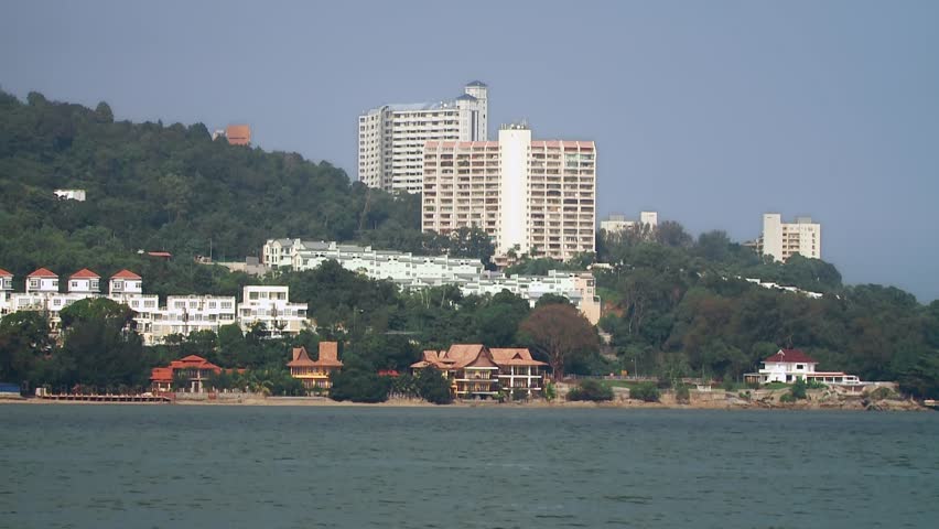 View of hillside houses and apartments surrounded by green trees in summer, with a river in the foreground, George Town, Penang, Malaysia