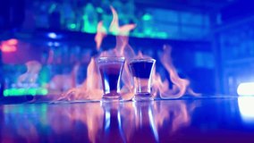 Glass of Alcoholic Drink on a Bar Counter Close-up. Bartender Prepares a Drink by Setting a Glass of Cocktail on Fire in a Nightclub. Bar in Neon Blue Lighting. Slow Motion. - Powered by Shutterstock - Get 15% off with code: PIKWIZARD15