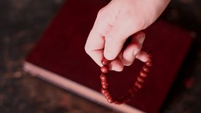 A man's hand is fingering a wooden rosary during a close-up prayer