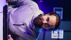 Vertical video Portrait of happy man focused on completing videogame in neon lit living room. Smiling gamer having gaming session, concentrating while competing in multiplayer tournaments - Powered by Shutterstock - Get 15% off with code: PIKWIZARD15