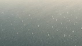 Aerial view of offshore wind farm with wind turbines on the North Sea, the Netherlands, Europe. Several large white and yellow wind turbines, wind mills on a blue, calm, sea. High quality 4K footage