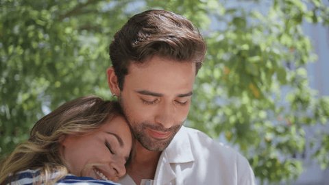 Lovely pair embracing together feeling happy at green garden closeup. Romantic couple bonding at nature date. Smiling newlyweds caressing each other on summer greenery background. Love relationships - Βίντεο στοκ