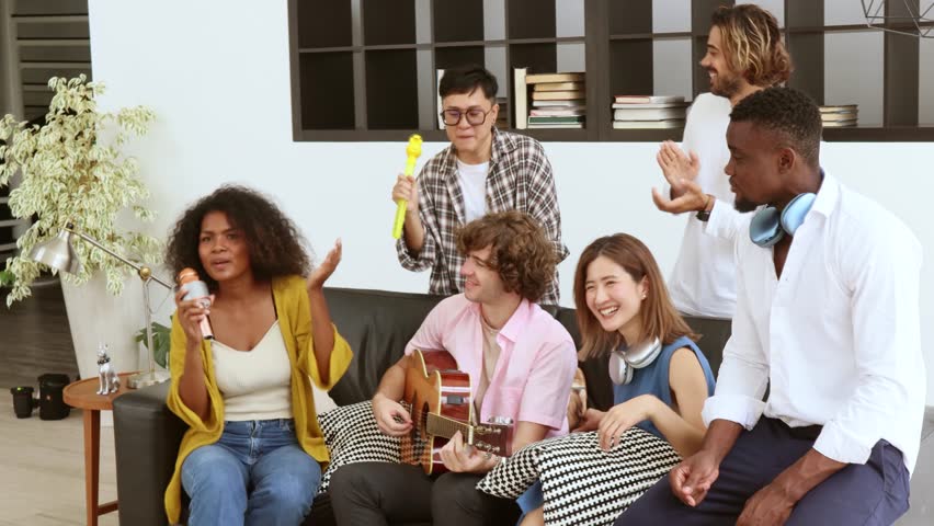 Multi-ethnic  friends and family are spending quality time together indoors, playing guitar, singing and dancing during the special holidays.  New year celebration concept with friends and family Royalty-Free Stock Footage #3400220817