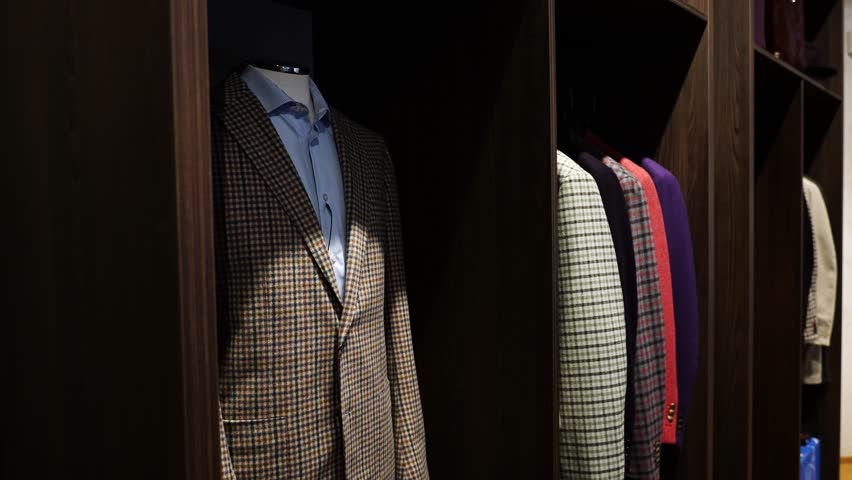Handmade plaid suits in different colors organized in open wood closet