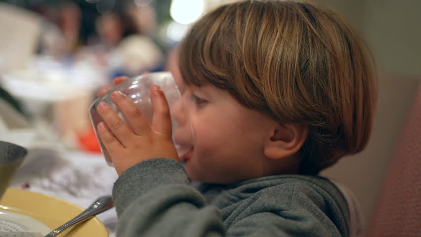 Closeup child drinking glass of water at restaurant. kid refreshing himself after meal, hydration concept