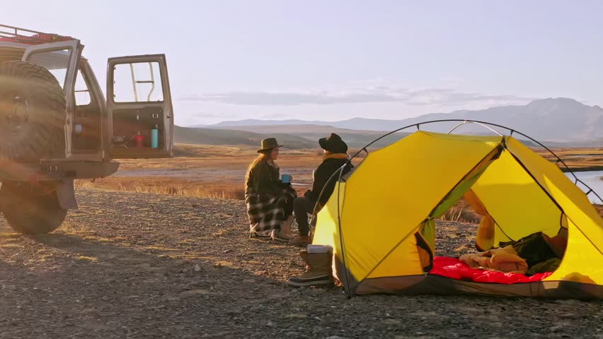 Group of Friends reparing coffee near travel suv. People enjoying a day camping. Autumn vacations and relationship concept. Picnic near car on sunset outside. Domestic travel concept.