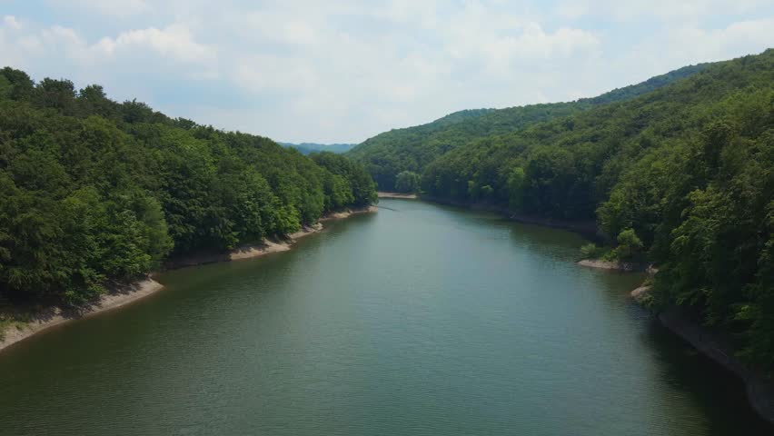 A three unrecognizable hunters walk towards deer stand in the meadow surrounded by woods and mountain