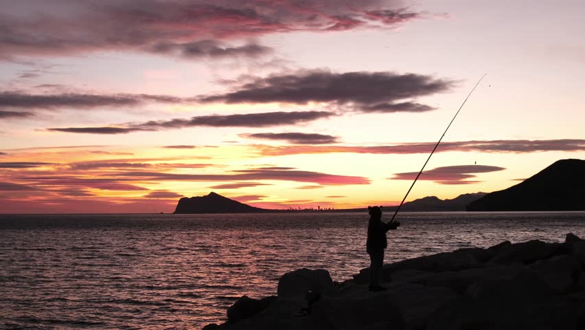 Reel of fishing rod hand rotation of orange sunset slow motion