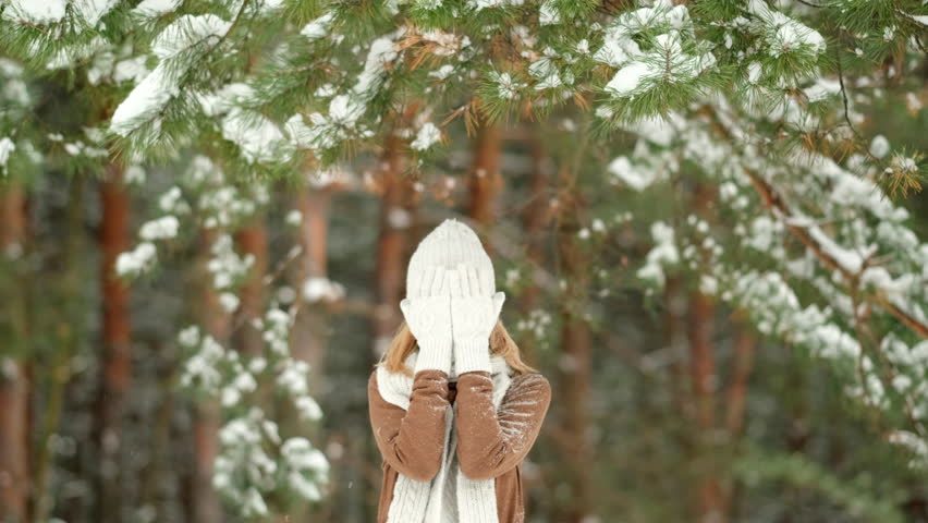 Snow winter weather. Snow falls on a female. Woman hides her face from the snow