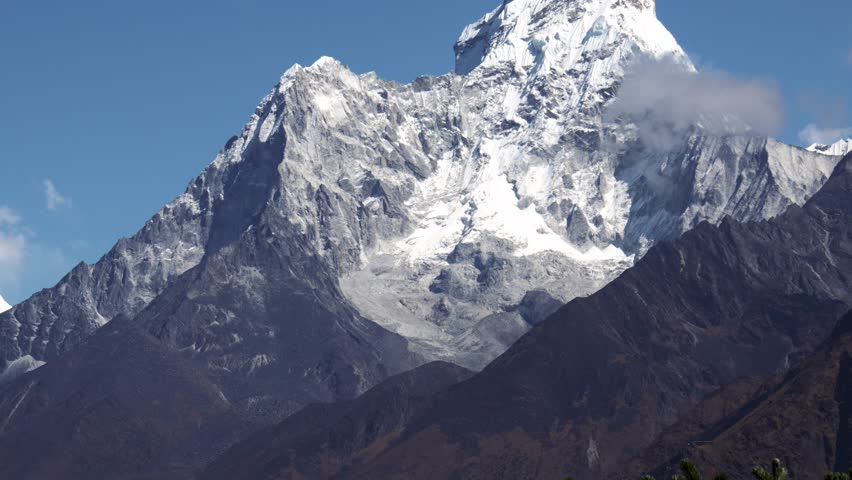 Snow covered Mount Ama Dablam rise above landscape of Himalayan Mountains. Trekking in Nepal to see highest mountains in world. Heat haze effect at hot sunny day. Royalty-Free Stock Footage #3400503849