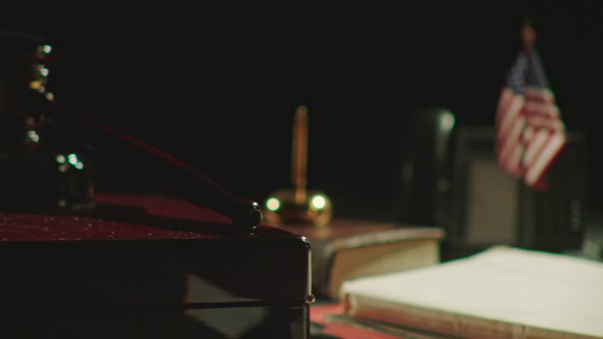 A closeup footage of wooden judge gavel on a desk with the American flag, telephone and pen and inkwell in the blur background. Justice concept