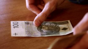Man counts money, cash Polish zloty, close-up 100 PLN, money on the table