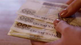 Woman counts money, cash Polish zloty, close-up 200 PLN, financial problems