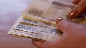 Woman counts money, cash Polish zloty, close-up 200 PLN, financial problems