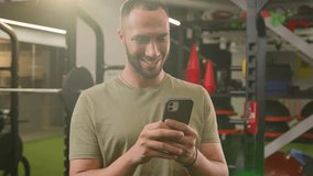 American Latino ethnic man athlete fit sport guy personal fitness trainer instructor male in gym bodybuilder sportsman using mobile phone happy smiling reading news in social media in smartphone app - Powered by Shutterstock - Get 15% off with code: PIKWIZARD15
