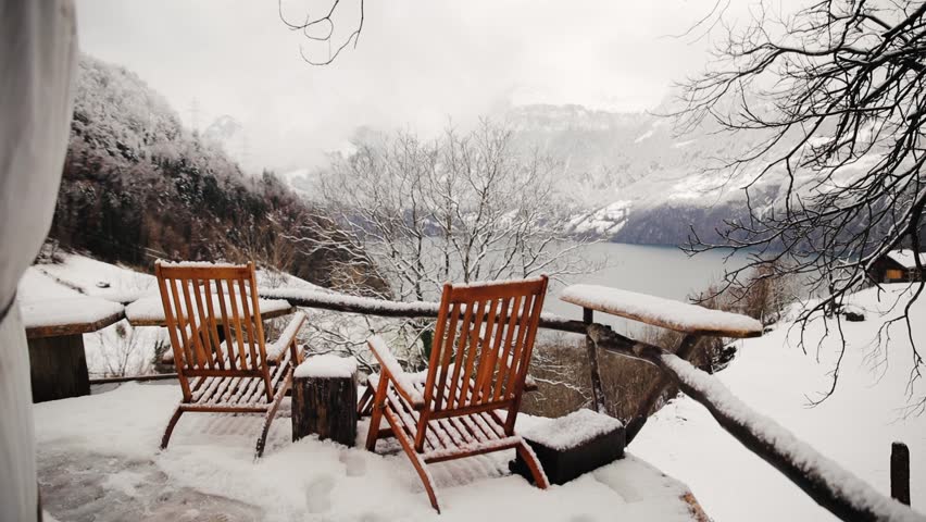 Two empty chairs covered with a snow against beautiful background view of Swiss Alps in winter season
