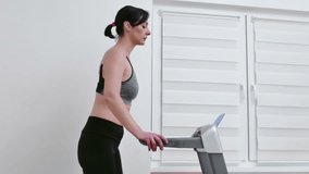 Young woman is exercising on a treadmill at home, Video Clip 4K