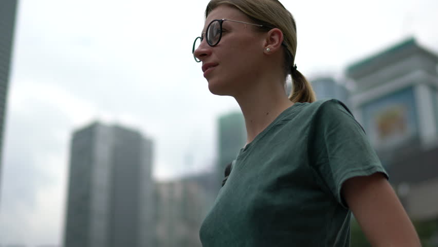 Attractive blonde tourist enjoying trip walking on city streets with modern architecture, young traveler enjoying walking in downtown