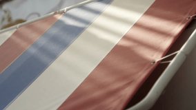 High-resolution slow-motion video of a blue and red striped fabric stretched taut within a metal frame, viewed from an overhead perspective