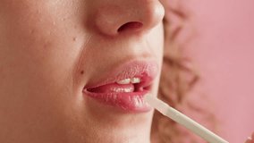 Beauty lip care. Young woman applying hygienic lipstick on lips close-up on pink background. Make-up routine - Powered by Shutterstock - Get 15% off with code: PIKWIZARD15
