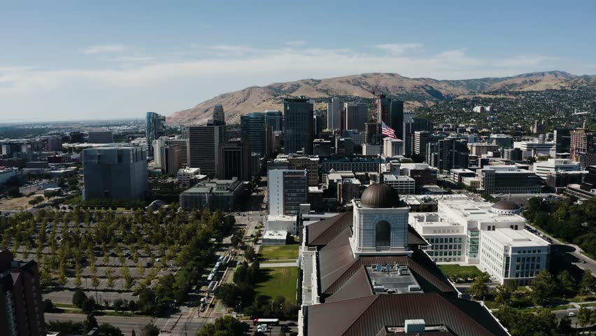 Drone shot pushing past the American flag waving over downtown Salt Lake City, Utah.