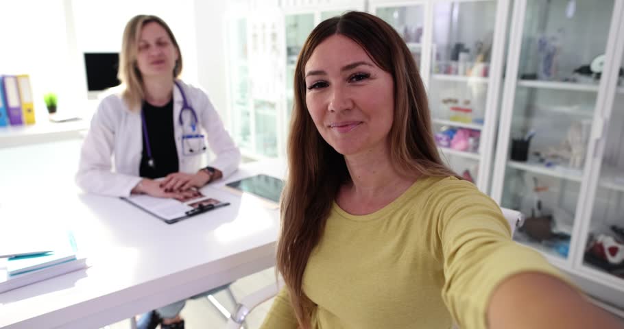 Smiling woman blogger takes selfie video in doctor office. Medical blog and doctor recommendation Royalty-Free Stock Footage #3400891615
