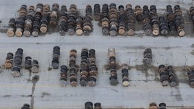 Aerial perspective of an outdoor warehouse, wooden cable drums stacked in organized rows. Cloudy drone footage.