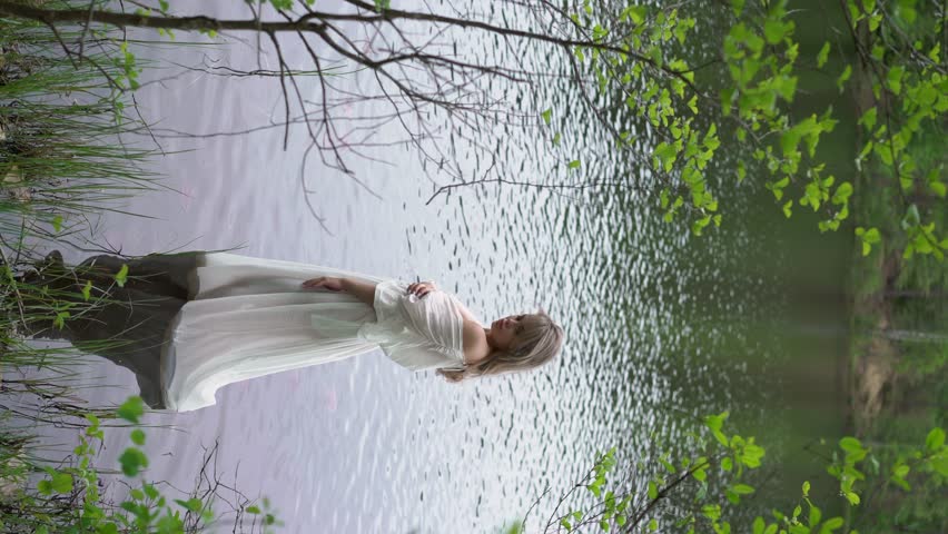 Woman Standing in Water in white transparent see-through long dress. Unrecognizable girl bathing in lake, pond or sea. Summer vibes. Bride in wedding morning. Boudoir of sexy female.
