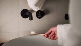 Woman washes toothbrush with running water in bathroom closeup. Lady in soft terry bathrobe cleans brush after teeth washing at home. Personal hygiene - Powered by Shutterstock - Get 15% off with code: PIKWIZARD15