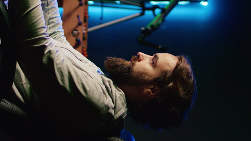 Vertical video Portrait of smiling man in dark living room playing engaging video games on gaming PC at computer desk, chilling after work. Happy gamer contending against foes in online multiplayer