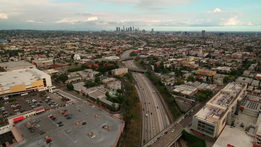 Aerial Backward Shot Of Cars Moving On Roads Amidst Residential Houses In City Under Clouds - Los Angeles, California