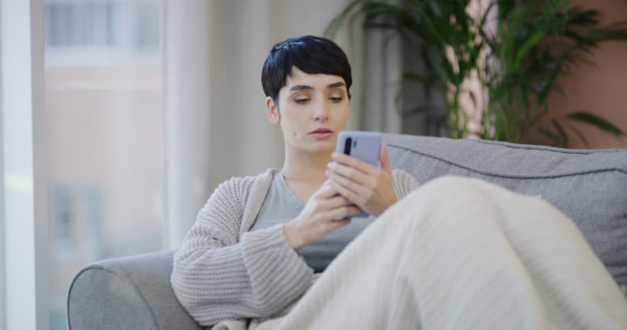 Phone, social media and relax with bored woman on sofa in living room of home for thinking or vision. Contact, app and communication with unhappy young person in apartment for mobile text message