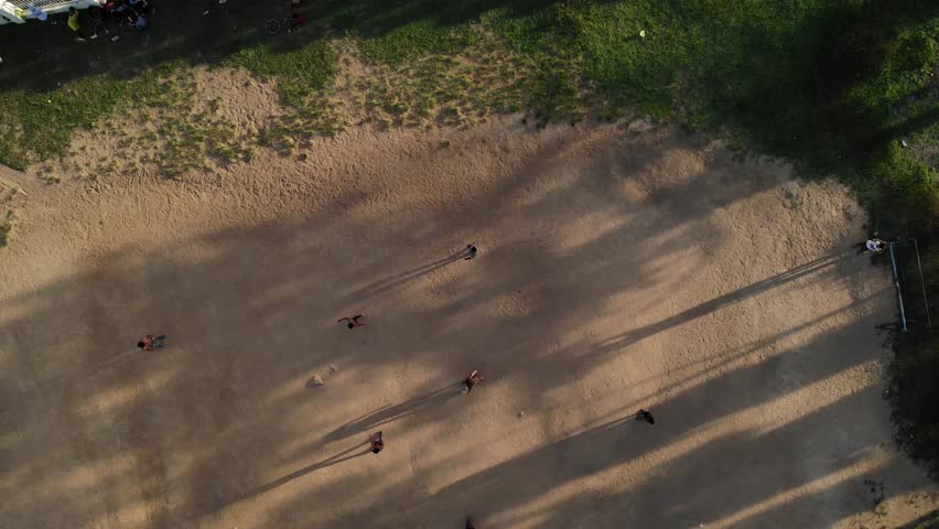 Silhouettes of small children playing football on a dirt field in Dam Rong, Lam Dong, Vietnam, viewed from above