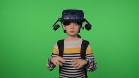 A little excited boy uses a virtual reality headset in a studio with a green background. The boy wears virtual reality glasses and turns his head around. - Powered by Shutterstock - Get 15% off with code: PIKWIZARD15