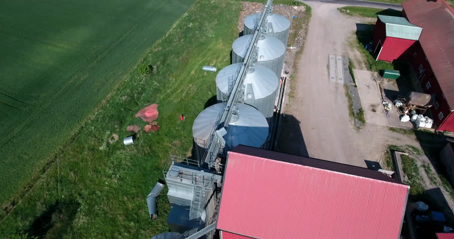 Aerial Tilt Up Shot Of Silos Outside Roofed Small Factories On Green Landscape On Sunny Day - Mariefred, Sweden