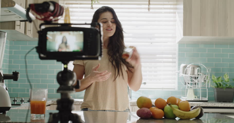 Woman, camera and live streaming in kitchen, education and juice tutorial or teaching at home. Female influencer, webinar and vlogger or technology for video recording, diet and fruit for nutrition