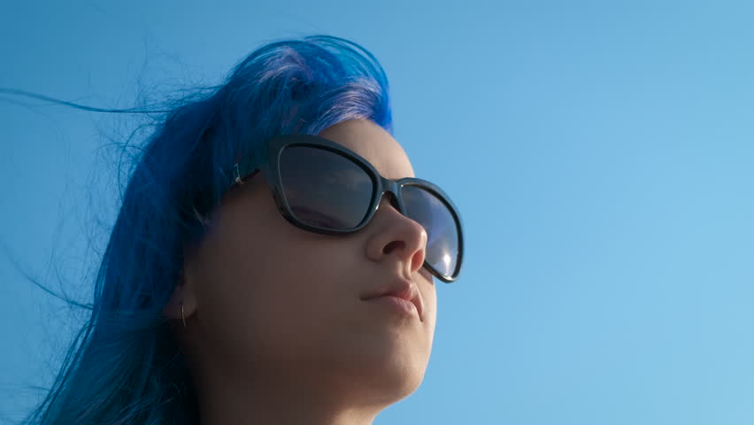 Girl with snimi hair in sunglasses. Stylish young girl in sunglasses against the sky.