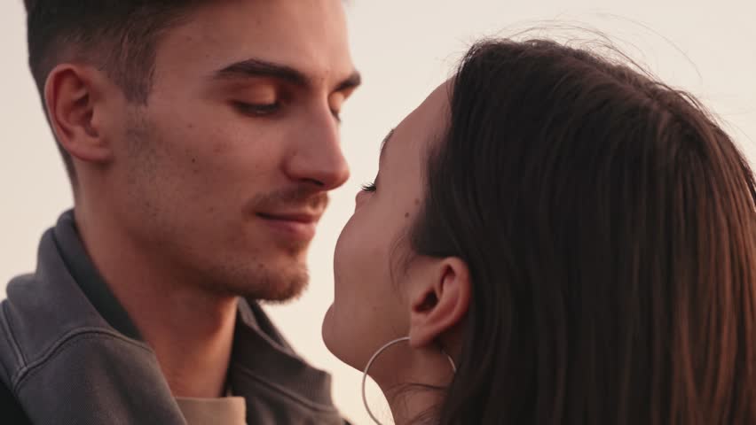 Captivating closeup of a couple's faces kissing passionately against the backdrop of a stunning sunset Royalty-Free Stock Footage #3401265373