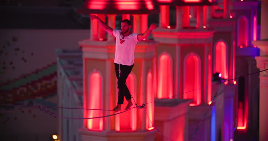 Balance and concentration, man is walking on slackline between buildings, 4k