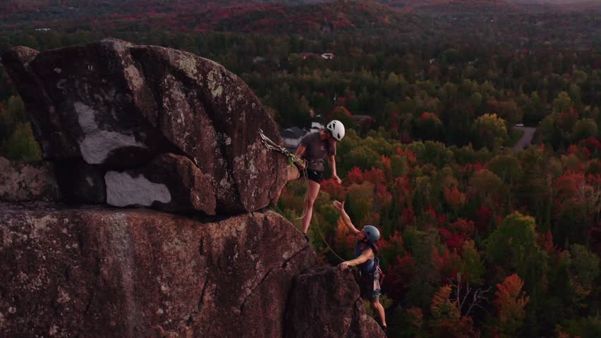 Young females rock climbing achievement with help from friend to reach summit