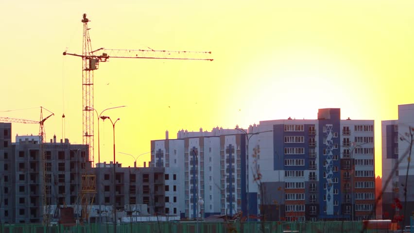 Tower cranes at sunset against the backdrop of an unfinished panel house and a new microdistrict. The concept of building houses on credit. Real estate on loan. Copy space for text, industry Royalty-Free Stock Footage #3401325711