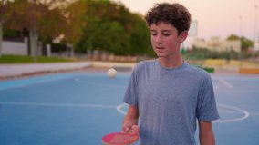 Teenager holding table tennis racket and bouncing ping pong ball. Slow motion film clip with sport equipment