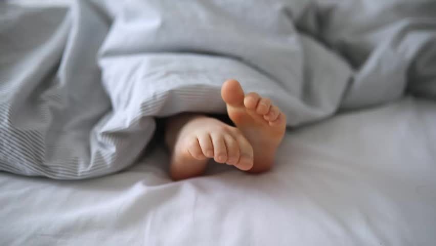 Little child's feet in bed covered with blanket Royalty-Free Stock Footage #3401387703