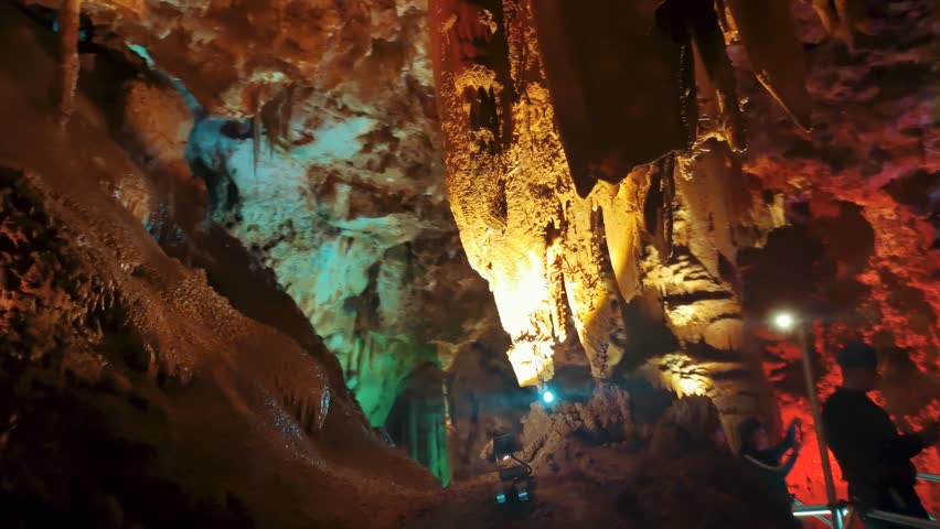 Venetsa Cave near Vidin, Bulgaria. Beautiful colorful and illuminated cave full with semiprecious onyx stones. Flowstones, stalactites and stalagmites lighted in different vivid colours. Royalty-Free Stock Footage #3401407007